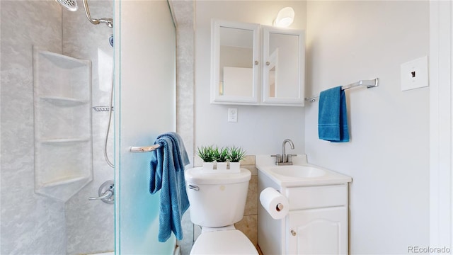 bathroom with toilet, vanity, and a tile shower