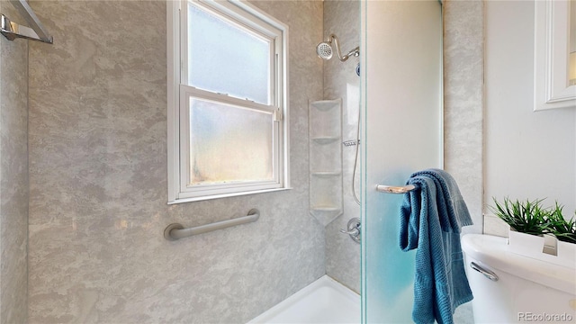 bathroom with toilet, a tile shower, and plenty of natural light