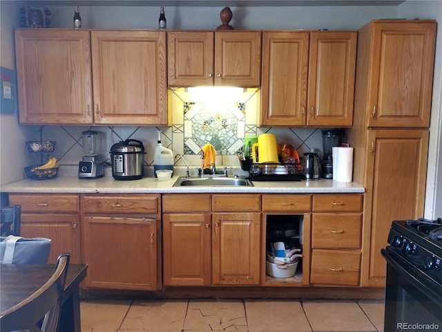 kitchen with gas stove, backsplash, light countertops, and a sink