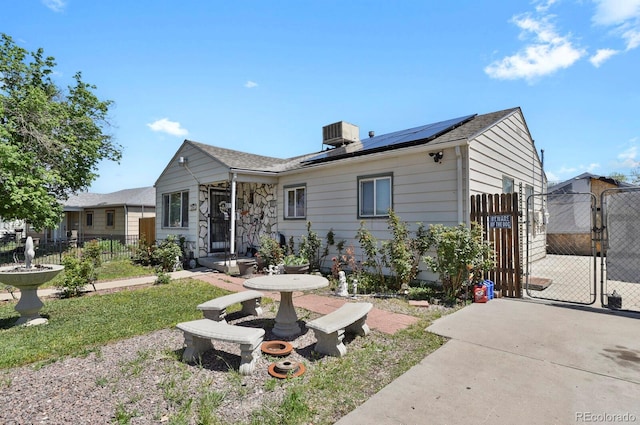 view of front facade with a gate, solar panels, fence, and central air condition unit
