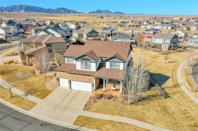 view of front facade featuring roof with shingles, an attached garage, a mountain view, a residential view, and driveway