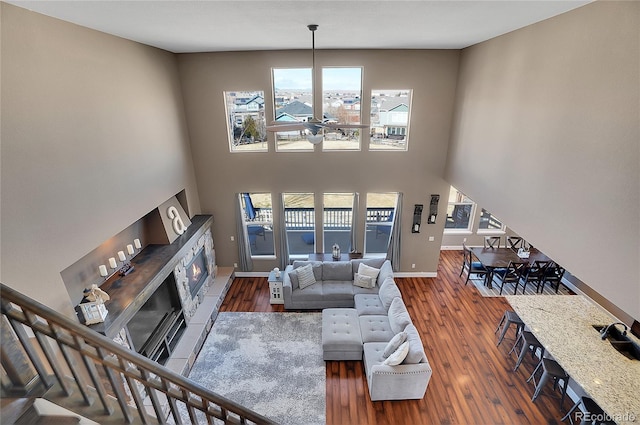 8726 Gardenia Cir, Arvada, CO 80005 - living area featuring a glass covered fireplace, wood finished floors, ceiling fan, a high ceiling, and baseboards