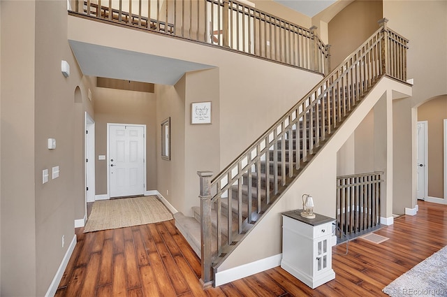 8726 Gardenia Cir, Arvada, CO 80005 - entrance foyer featuring arched walkways, a towering ceiling, baseboards, wood finished floors, and stairway
