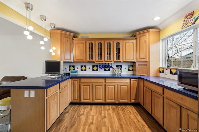 kitchen featuring stainless steel microwave, a breakfast bar area, a peninsula, and dark countertops