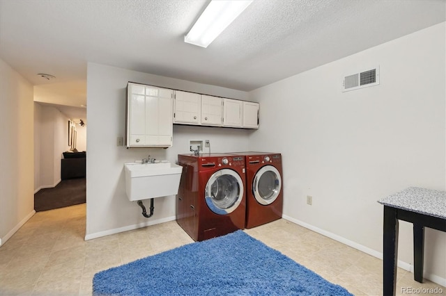 washroom with visible vents, baseboards, cabinet space, a textured ceiling, and separate washer and dryer