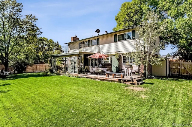 rear view of property featuring a yard, fence, a chimney, and a wooden deck