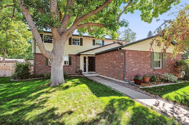 traditional-style home with brick siding, a front yard, and fence