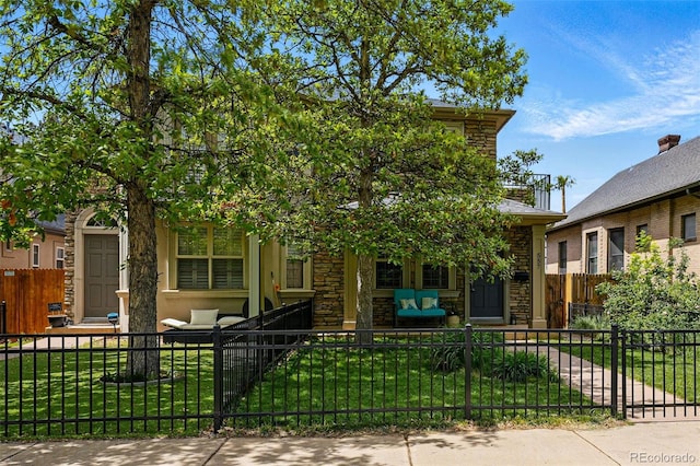 view of property hidden behind natural elements featuring stone siding and covered porch