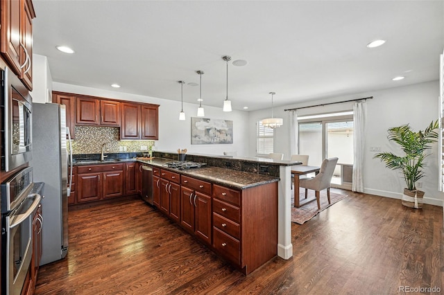 kitchen with stainless steel appliances, dark wood-style floors, a sink, a peninsula, and recessed lighting