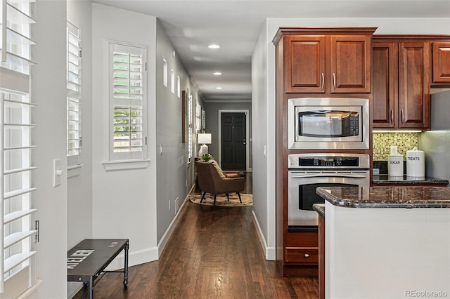kitchen with stainless steel appliances, dark wood finished floors, dark stone counters, recessed lighting, and baseboards