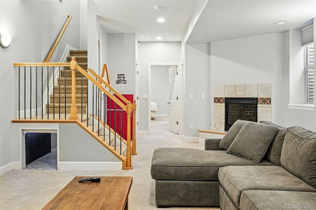 living room featuring carpet flooring, stairs, a tile fireplace, baseboards, and recessed lighting