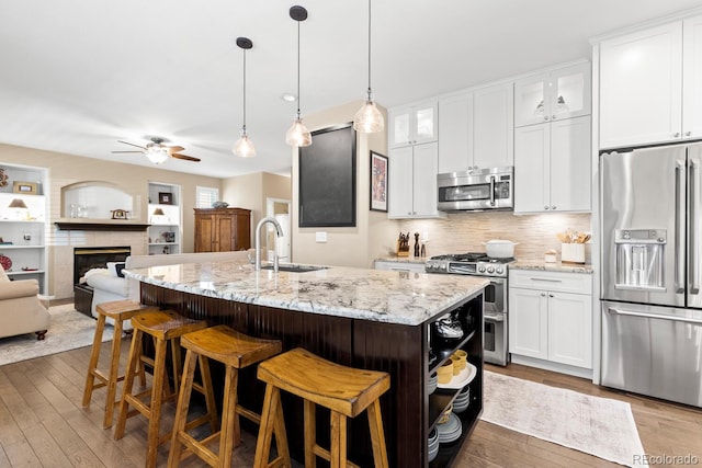 6772 Tiger Tooth, Littleton, CO 80124 - kitchen featuring appliances with stainless steel finishes, ceiling fan, wood-type flooring, white cabinetry, and a center island with sink
