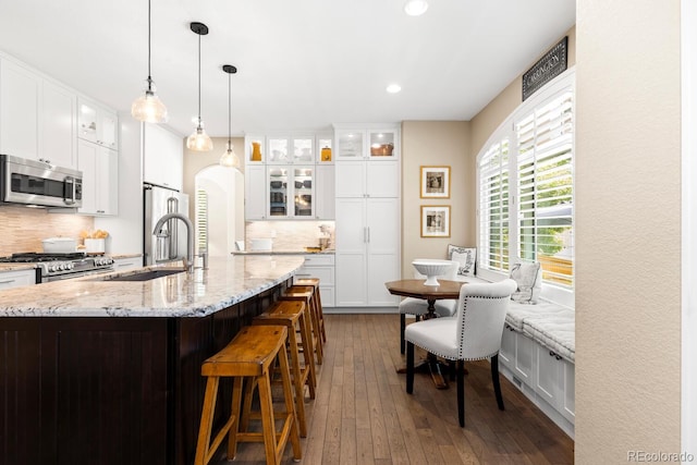 6772 Tiger Tooth, Littleton, CO 80124 - kitchen with stainless steel appliances, decorative backsplash, dark wood finished floors, white cabinets, and recessed lighting