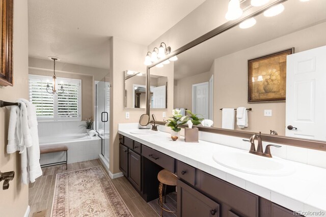 6772 Tiger Tooth, Littleton, CO 80124 - bathroom with double vanity, a garden tub, a shower stall, wood finished floors, and a chandelier