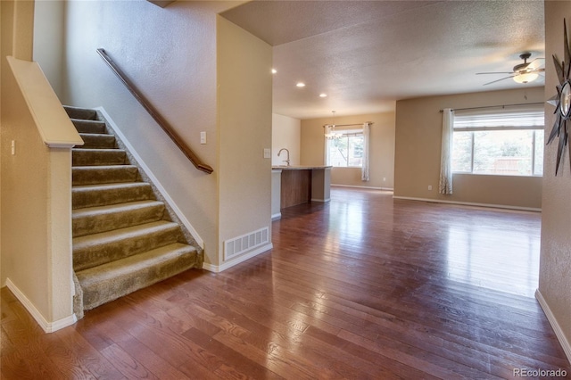 5947 Cumbre Vista Way, Colorado Springs, CO 80924 - unfurnished living room featuring dark wood-type flooring, a ceiling fan, stairs, and a textured ceiling