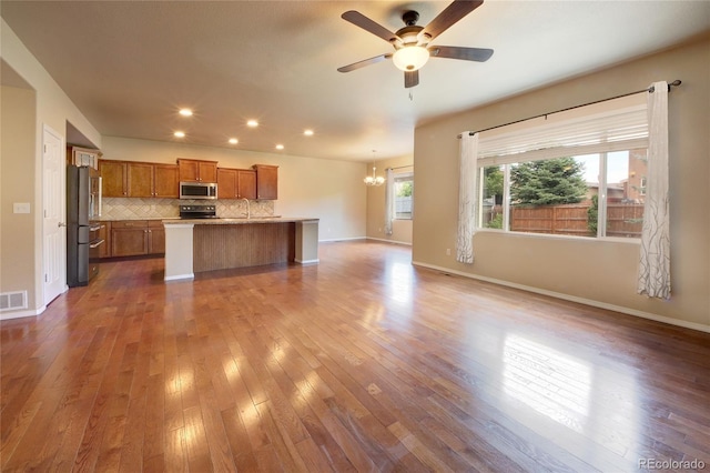 5947 Cumbre Vista Way, Colorado Springs, CO 80924 - kitchen featuring stainless steel microwave, open floor plan, brown cabinetry, freestanding refrigerator, and light countertops