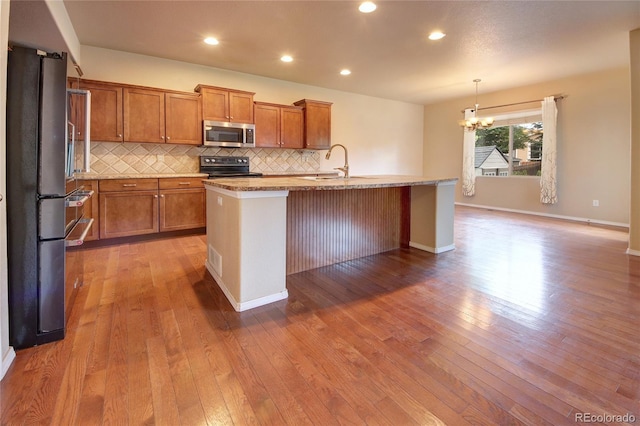 5947 Cumbre Vista Way, Colorado Springs, CO 80924 - kitchen featuring stainless steel microwave, black electric range, a chandelier, freestanding refrigerator, and brown cabinetry