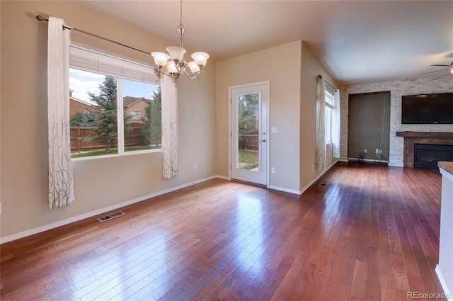 5947 Cumbre Vista Way, Colorado Springs, CO 80924 - unfurnished living room with a chandelier, healthy amount of natural light, wood-type flooring, and a stone fireplace