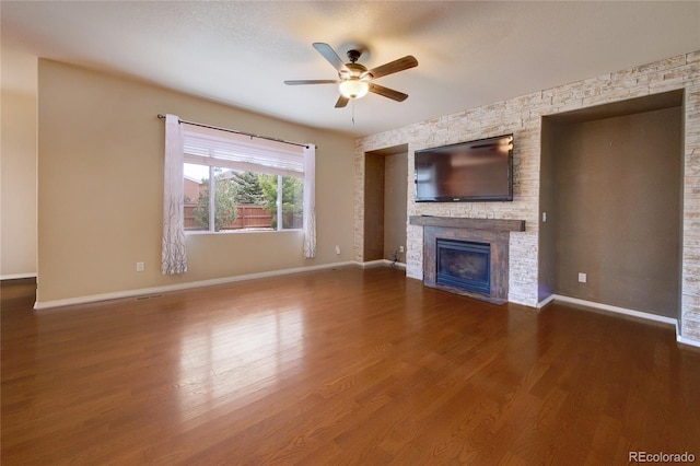 5947 Cumbre Vista Way, Colorado Springs, CO 80924 - unfurnished living room with ceiling fan, a stone fireplace, and dark wood-style floors