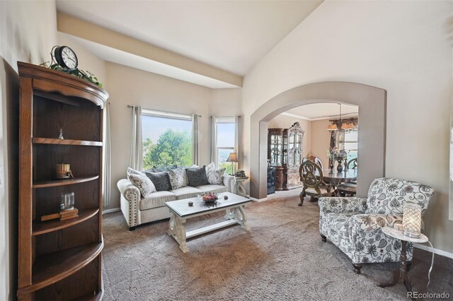 living room with carpet floors, arched walkways, and high vaulted ceiling