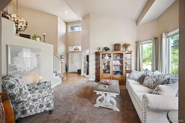 carpeted living area with a towering ceiling, plenty of natural light, stairway, and a notable chandelier