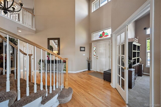 entryway with stairway, wood finished floors, a towering ceiling, and baseboards