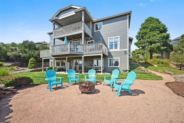 back of property with a fire pit, a patio, and a lawn