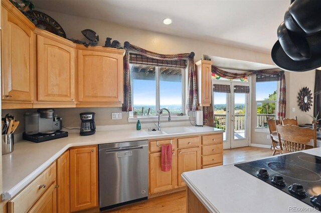 kitchen with black electric stovetop, light countertops, stainless steel dishwasher, light wood-style floors, and a sink