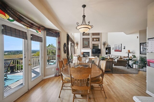 dining space with a glass covered fireplace, french doors, light wood-style flooring, and baseboards