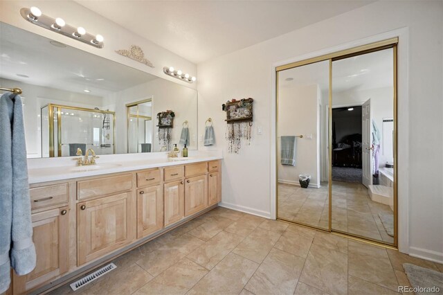 full bathroom with double vanity, visible vents, a sink, a shower stall, and baseboards