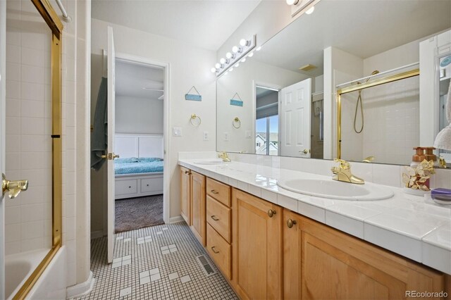 ensuite bathroom featuring double vanity, a shower with door, ensuite bath, tile patterned flooring, and a sink