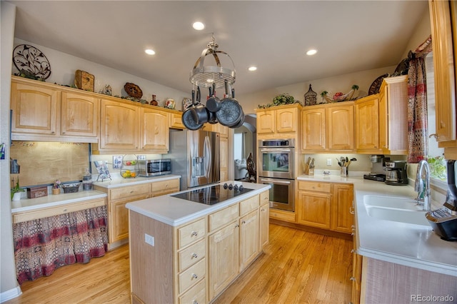 kitchen featuring appliances with stainless steel finishes, a center island, light countertops, light wood-style floors, and a sink