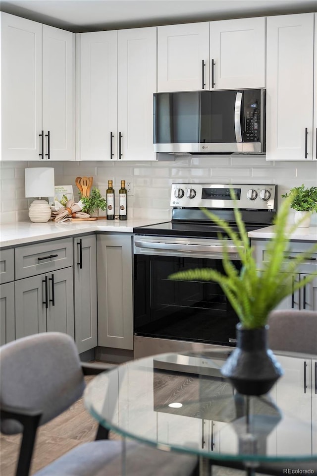 4901 W 11th Ave, Denver, CO 80204 - kitchen featuring appliances with stainless steel finishes, light countertops, backsplash, and white cabinets