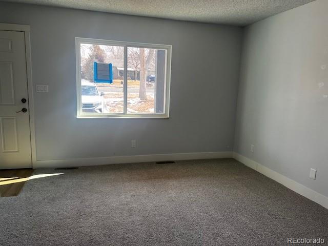 carpeted empty room featuring baseboards and a textured ceiling