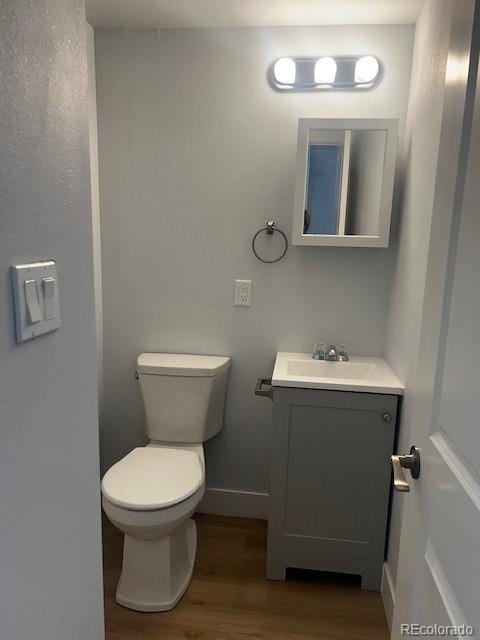 bathroom featuring baseboards, vanity, toilet, and wood finished floors