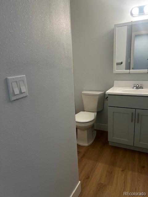 bathroom featuring vanity, wood finished floors, toilet, and baseboards