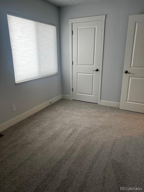 spare room featuring carpet floors and baseboards