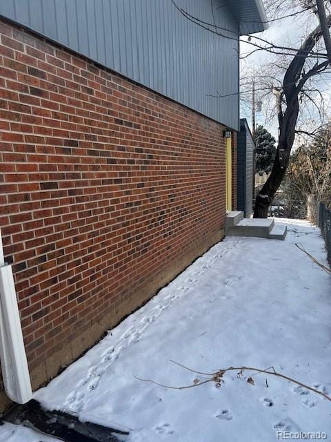 view of snow covered exterior with brick siding