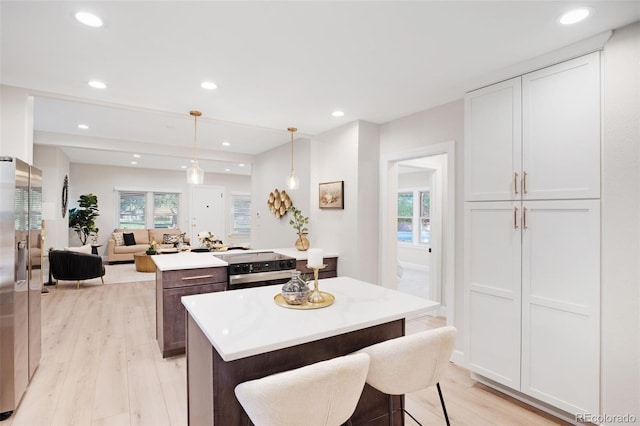 kitchen featuring white cabinetry, a kitchen island, pendant lighting, and a kitchen bar