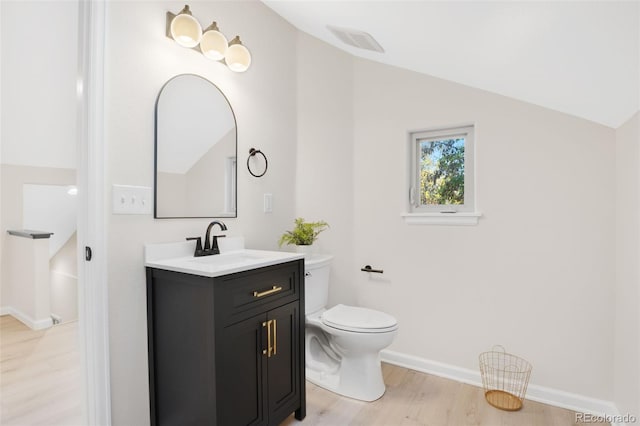 bathroom featuring hardwood / wood-style flooring, vanity, toilet, and vaulted ceiling