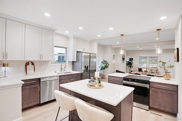 kitchen featuring sink, dark brown cabinets, hanging light fixtures, appliances with stainless steel finishes, and white cabinets