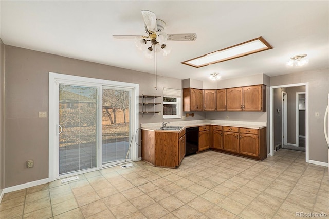 kitchen with brown cabinetry, a skylight, a sink, light countertops, and dishwasher