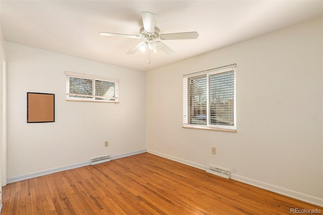 empty room with light wood-style flooring, visible vents, and a wealth of natural light