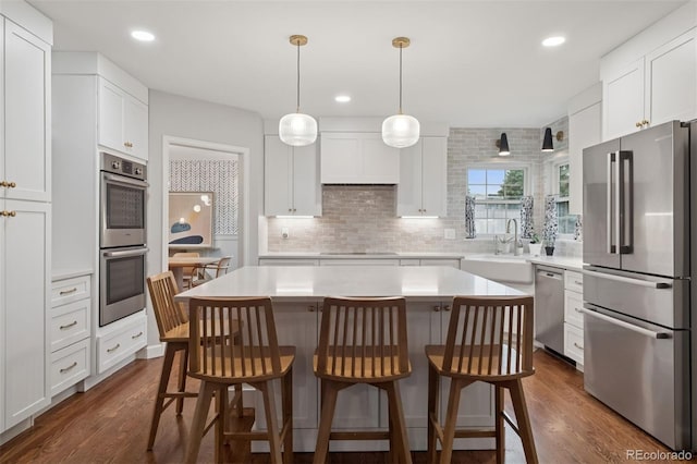 3566 E Meadow Creek Pl, Highlands Ranch, CO 80126 - kitchen featuring appliances with stainless steel finishes, a sink, a kitchen bar, light countertops, and recessed lighting
