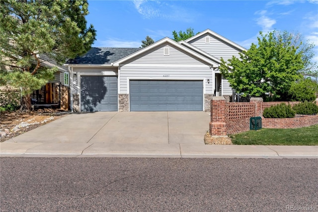single story home featuring a garage, concrete driveway, fence, and stone siding