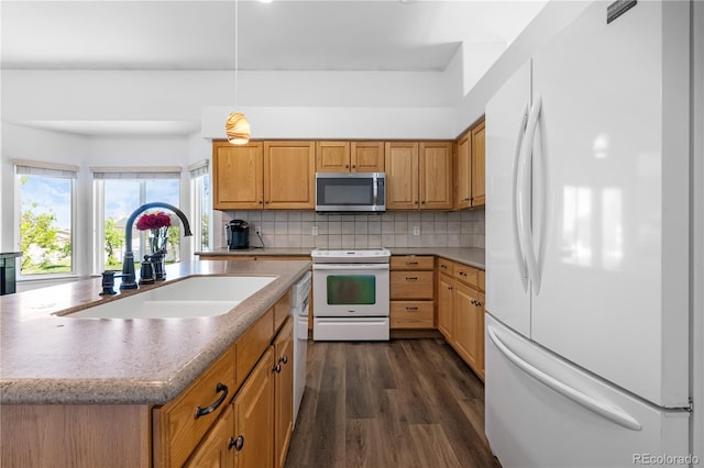 kitchen featuring white appliances, a sink, dark wood-style flooring, backsplash, and a kitchen island with sink