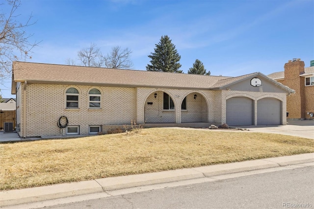 single story home featuring driveway, roof with shingles, a front yard, a garage, and brick siding