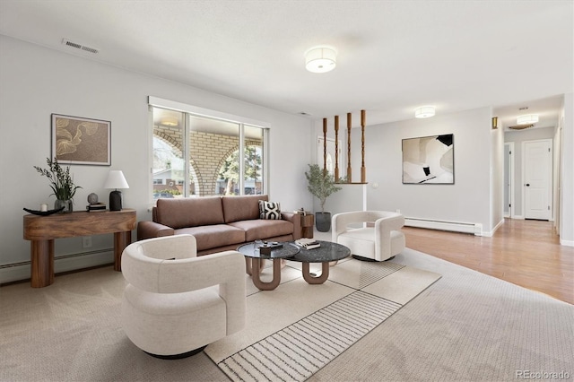 living area featuring a baseboard heating unit, light wood-style floors, baseboards, and visible vents