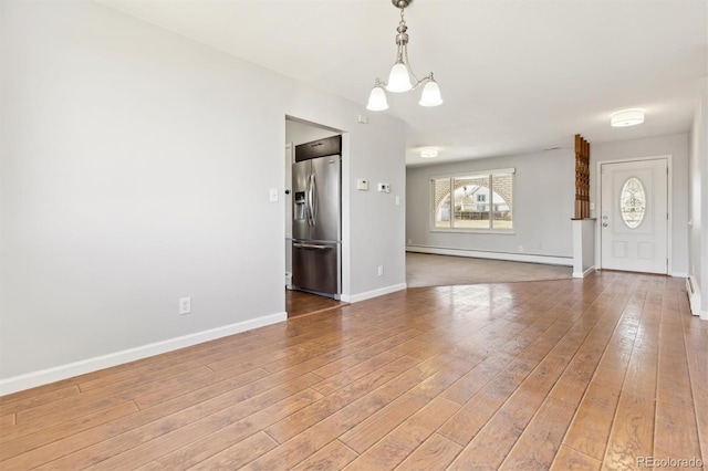 unfurnished living room featuring a baseboard heating unit, baseboards, hardwood / wood-style floors, baseboard heating, and a notable chandelier