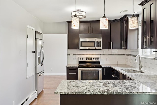 kitchen with backsplash, dark brown cabinets, light wood-style flooring, stainless steel appliances, and a sink